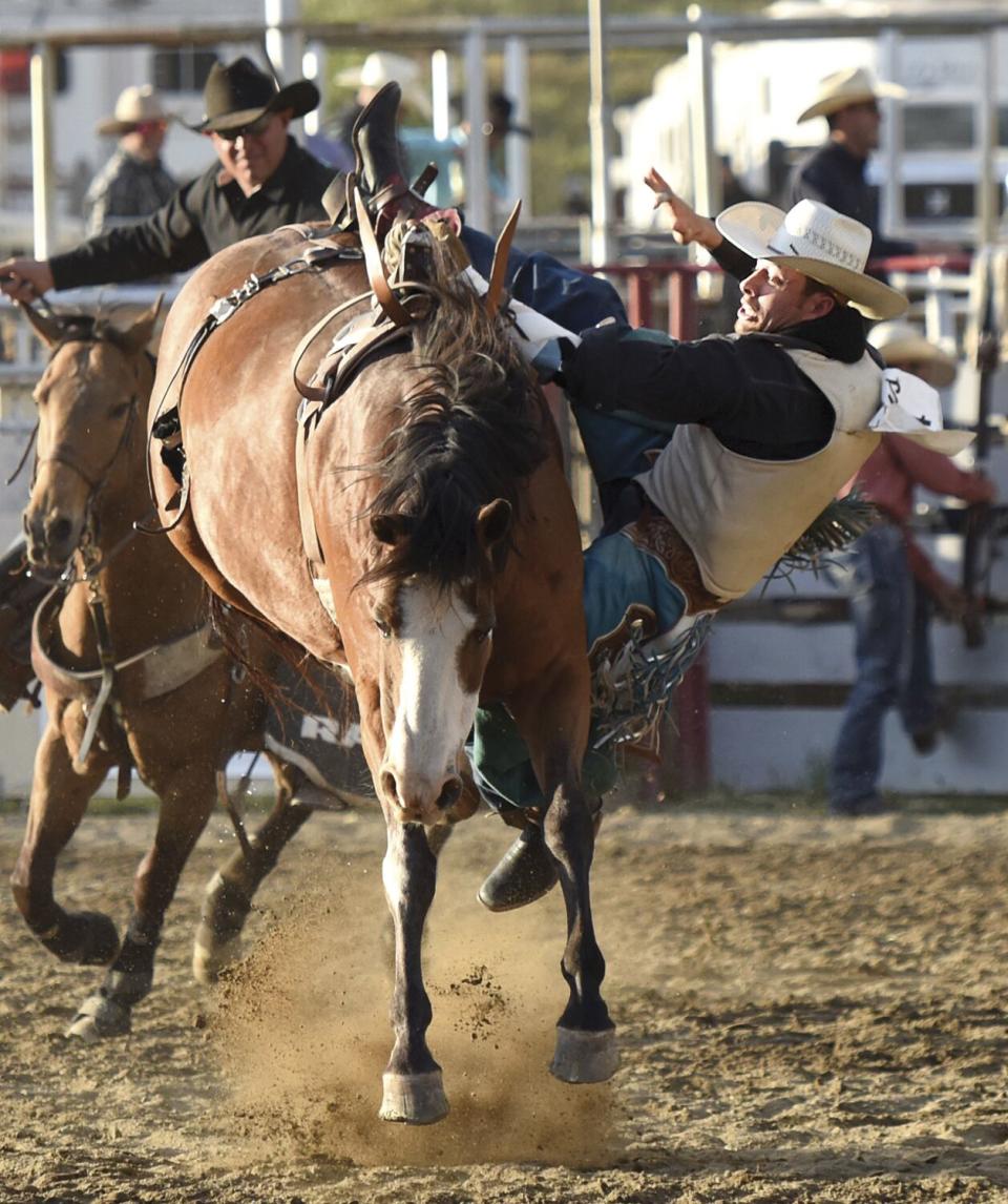 A man is hanging on to the side of horse.