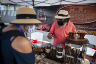 Tourists look at cigars for sale at the Old San Juan dock after the arrival of Carnival's Mardi Gras cruise ship in San Juan, Puerto Rico, Tuesday, Aug. 3, 2021, marking the first time a cruise ship visits the U.S. territory since the COVID-19 pandemic began. (AP Photo/Carlos Giusti)