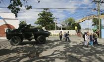 Residents walk past a government military vehicle as they evacuate near an area where members of Muslim rebels Moro National Liberation Front (MNLF) have occupied in Zamboanga city, southern Philippines September 9, 2013. Muslim rebels took 30 civilian hostages in the southern Philippines on Monday and held security forces in a standoff as part of a drive to derail peace talks, officials said. Police commandos cordoned off parts of Zamboanga city on the island of Mindanao after a rogue faction of the MNLF took hostages and tried to march to the city hall to raise their flag, an army commander said. REUTERS/Stringer (PHILIPPINES - Tags: POLITICS MILITARY CIVIL UNREST)