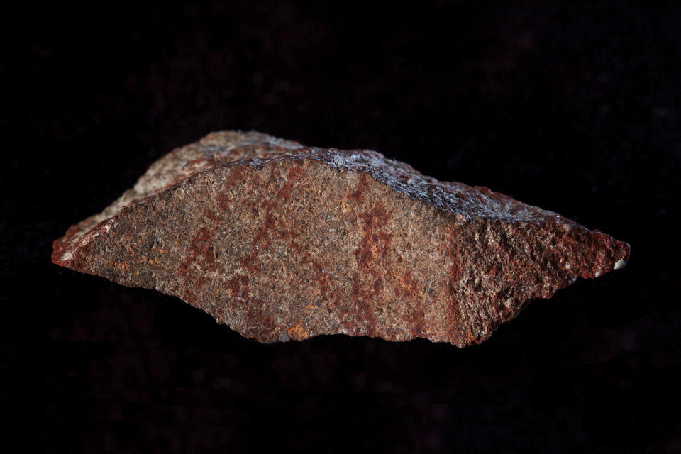 This undated photo provided by Craig Foster in September 2018 shows a drawing made with ochre pigment on silcrete stone, found in the Blombos Cave east of Cape Town, South Africa. In a report released on Wednesday, Sept. 12, 2018, scientists say this tiny 73,000-year-old sketch found in a South African cave is the oldest known drawing. (Craig Foster via AP)
