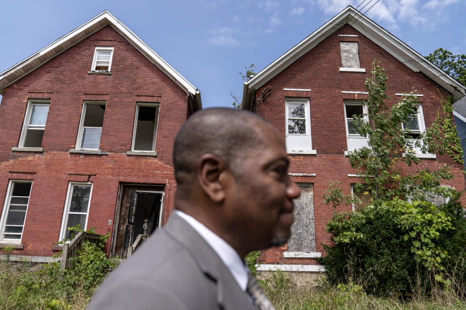 Rev. Jimmie Hardaway Jr. walks past blighted homes near Trinity Baptist Church Sunday, Aug. 20, 2023, in Niagara Falls, N.Y. The decision Hardaway made to carry a weapon is a distinctly American one. And it spotlights rising friction between the assertion of two very American principles: the right to worship and the right to own guns. With U.S. deaths by gunfire reaching record levels, it is far from an isolated instance of that tension. (AP Photo/David Goldman)