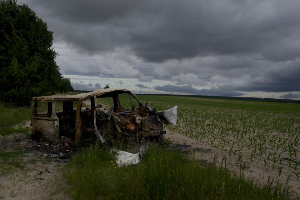 The wreckage of a burned out van that triggered an anti-tank mine, killing its three occupants, lies by the side of a dirt track in Andriyivka, on the outskirts of Kyiv, Ukraine, Tuesday, June 14, 2022. Russia’s invasion of Ukraine is spreading a deadly litter of mines, bombs and other explosive devices that will endanger civilian lives and limbs long after the fighting stops. (AP Photo/Natacha Pisarenko)