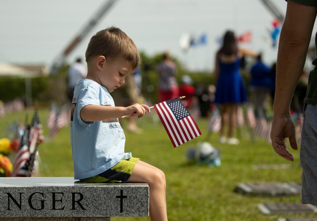 Joseph Gill, 2, of Cape Coral waves a flag at his first Memorial Day ceremony on Monday, May 29, 2023, at Coral Ridge Cemetery in Cape Coral. Gill and his dad were among the crowd of around 400 people who came to commemorate Memorial Day. 