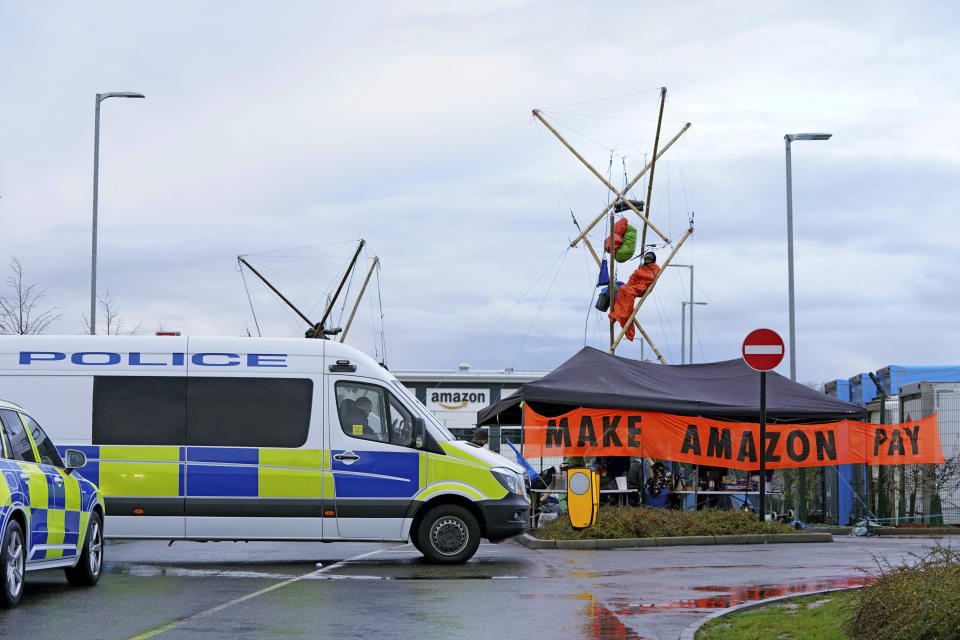 Activists from Extinction Rebellion block the entrance to the Amazon fulfilment centre preventing lorries from entering or leaving on Black Friday, the global retail giant's busiest day of the year, in Coventry, England, Friday, Nov. 26, 2021. The group has targeted Amazon sites in Doncaster, Darlington, Dunfremline, Newcastle, Manchester, Peterborough, Derby, Coventry, Rugeley, Dartford, Bristol, Tilbury and Milton Keynes. (Joe Giddens/PA via AP)