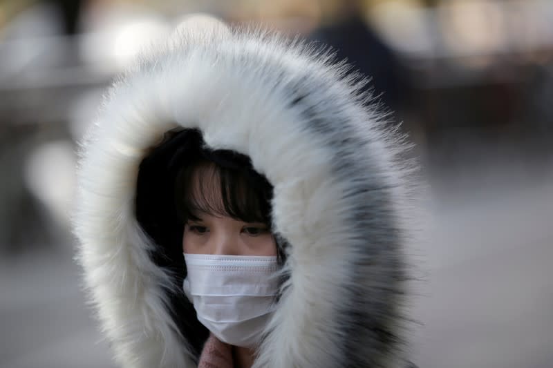 Woman wearing a mask walks along a street in Beijing