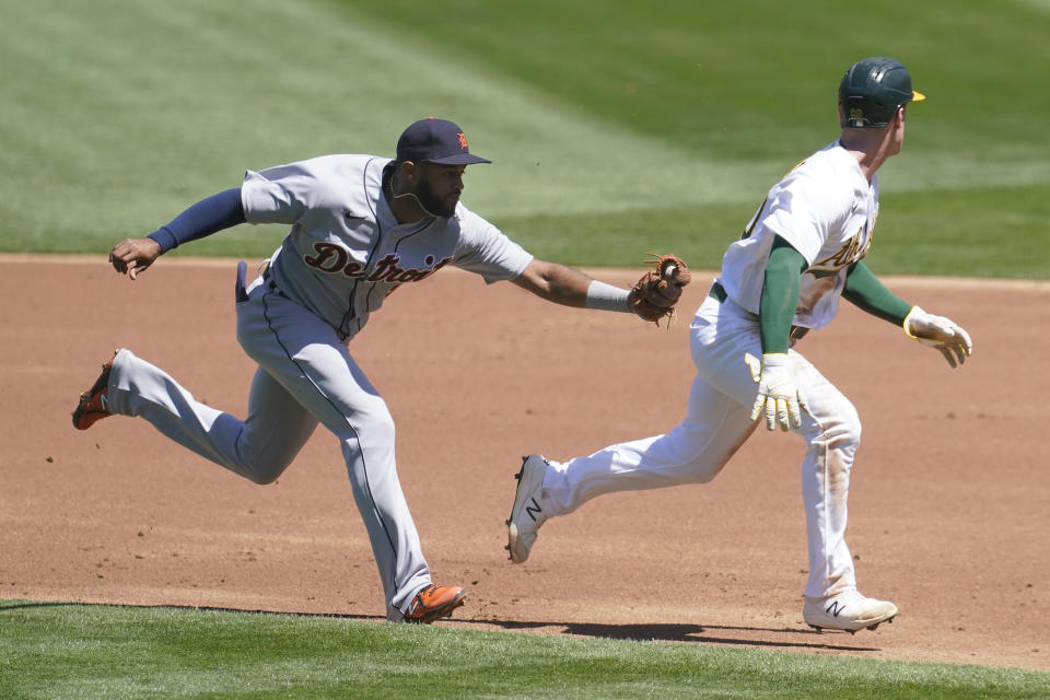 Oakland Athletics Mark Canha, right, is caught in a rundown before being tagged out by Detroit Tigers shortstop Willi Castro, left, during the first inning of a baseball game in Oakland, Calif., Sunday, April 18, 2021. (AP Photo/Jeff Chiu)