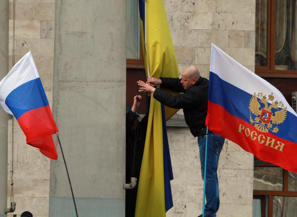 Activistas a favor de Rusia retiran la bandera de Ucrania (centro) para reemplazarla por una rusa en una oficina de gobierno en Donetsk, Ucrania, el sábado 1 de marzo de 2014. (Foto AP/Sergey Vaganov)