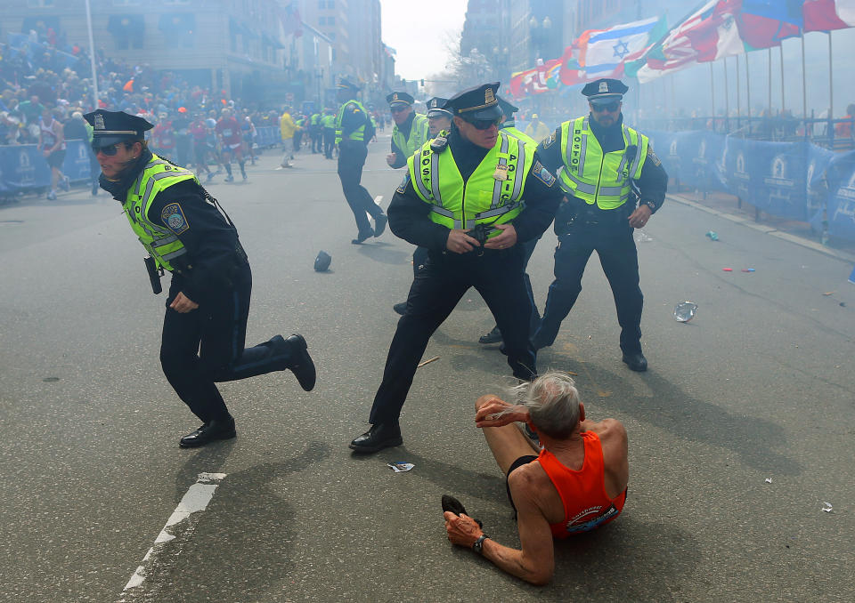 Police officers with their guns drawn hear the second explosion down the street t the Boston Marathon. The first explosion knocked down 78-year-old US marathon runner Bill Iffrig at the finish line of the 117th Boston Marathon. (John Tlumacki/The Boston Globe via Getty Images)