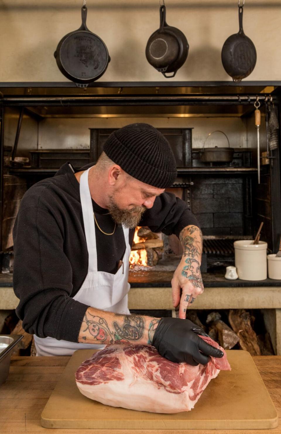 Chef-owner Brian Dunsmoor carves pork shoulder for his pork and green chile stew.