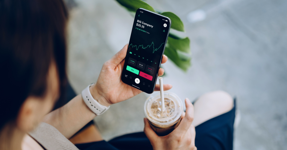 A young woman looks at a stock price on her phone.