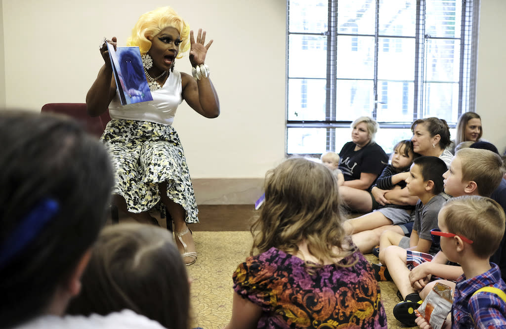 A person dressed in drag reading a story to a group of children.