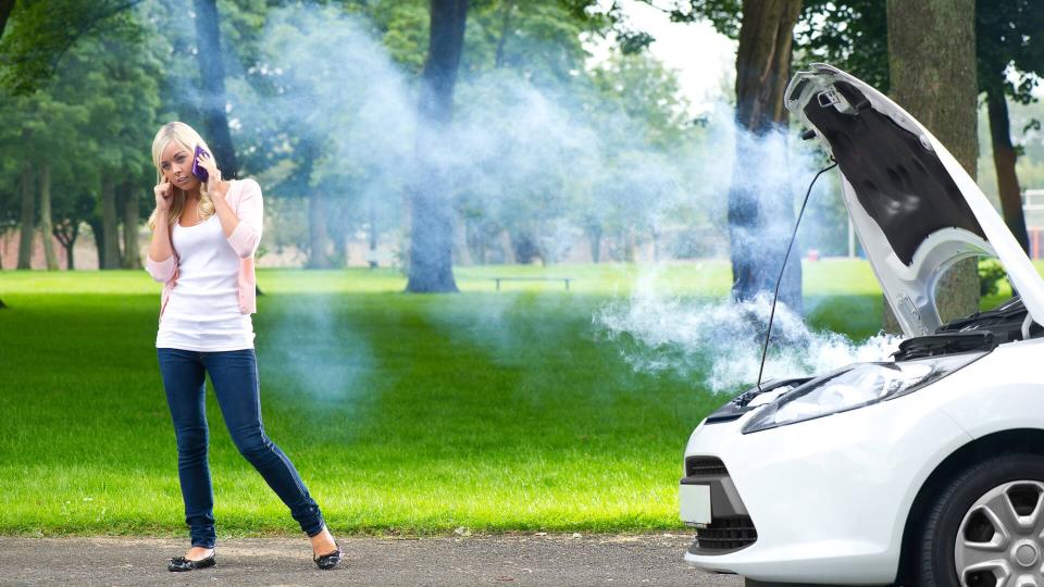 young woman stands by her broken car .