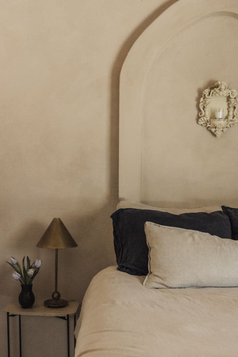 Bedroom with warm neutral textured walls and relief arch over bed