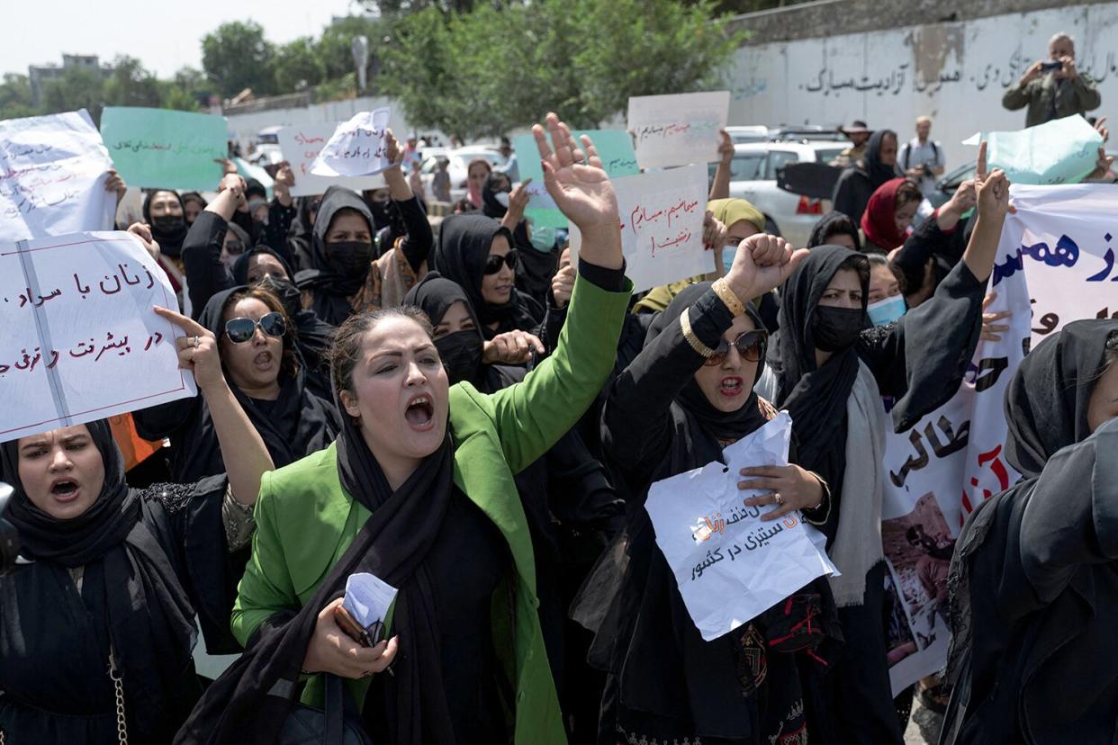 Afghan women hold placards as they march and shout slogans "Bread, work, freedom" during a womens' rights protest in Kabul on August 13, 2022. - Taliban fighters beat women protesters and fired into the air on Saturday as they violently dispersed a rare rally in the Afghan capital, days ahead of the first anniversary of the hardline Islamists' return to power.