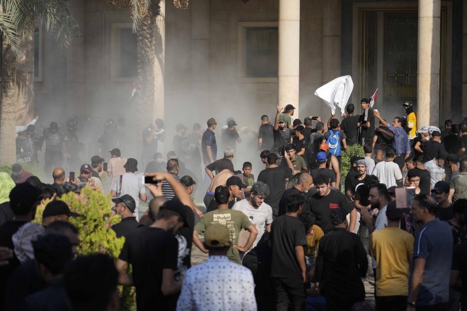 Iraqi security forces fire tear gas on followers of Shiite cleric Muqtada al-Sadr protesting inside the government palace grounds, in Baghdad, Iraq, Monday, Aug. 29, 2022. Al-Sadr, a hugely influential Shiite cleric announced he will resign from Iraqi politics and his angry followers stormed the government palace in response. The chaos Monday sparked fears that violence could erupt in a country already beset by its worst political crisis in years. (AP Photo/Hadi Mizban)