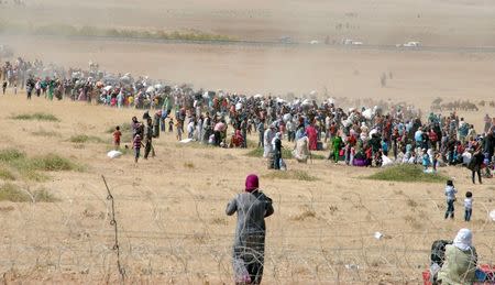 Syrian Kurds wait behind the border fence to cross into Turkey near the southeastern town of Suruc in Sanliurfa province, September 19, 2014. S REUTERS/Stringer