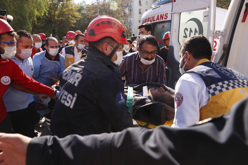 Medics and rescue personnel carry into an ambulance an injured person from the debris of a collapsed building in Izmir, Turkey, Saturday, Oct. 31, 2020. Rescue teams on Saturday ploughed through concrete blocs and debris of eight collapsed buildings in Turkey's third largest city in search of survivors of a powerful earthquake that struck Turkey's Aegean coast and north of the Greek island of Samos, killing dozens Hundreds of others were injured. (AP Photo/Darko Bandic)