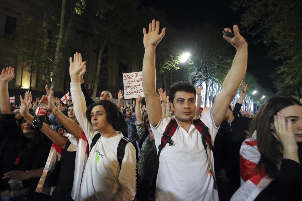 Demonstrators react listening to a speaker as they gather outside the parliament building in Tbilisi, Georgia, on Wednesday, April 17, 2024, to protest against "the Russian law" similar to a law that Russia uses to stigmatize independent news media and organizations seen as being at odds with the Kremlin. (AP Photo/Zurab Tsertsvadze)