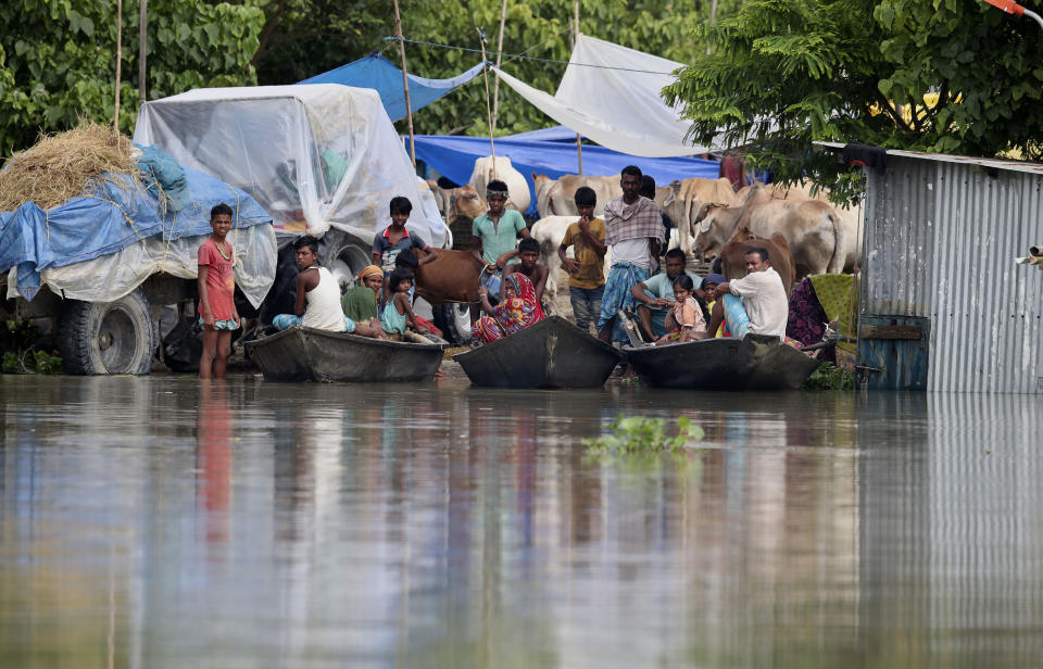 Indian flood affected villagers and cattle take shelter on a partially washed away road in Gagolmari village, Morigaon district, Assam, India, Tuesday, July 14, 2020. Hundreds of thousands of people have been affected by floodwaters and landslides following incessant rainfall in the region. (AP Photo/Anupam Nath)