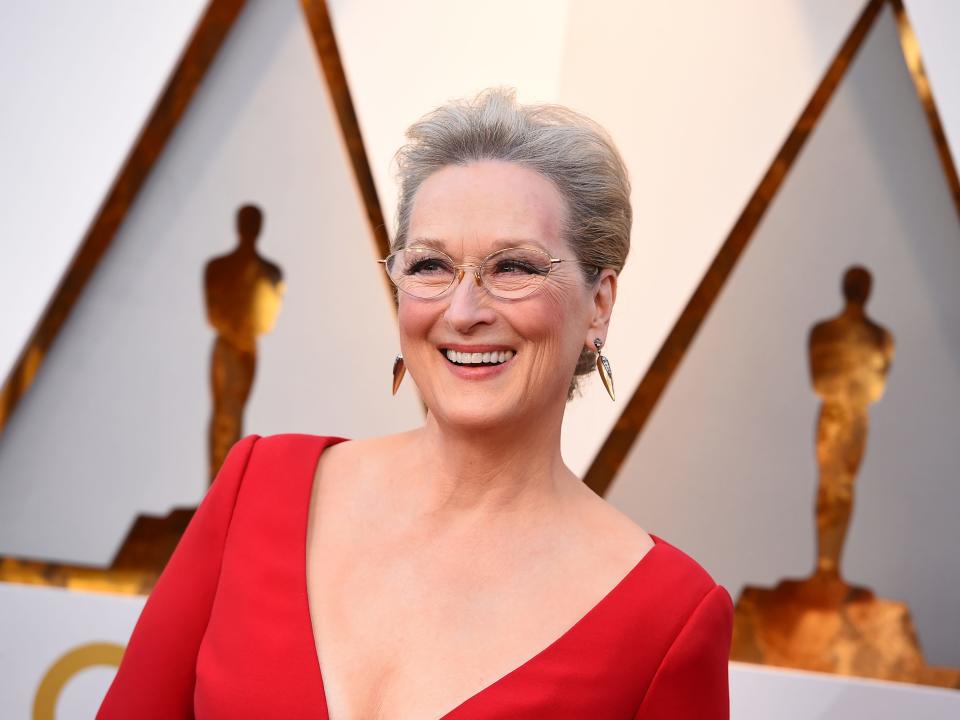 Meryl in a red plunging neck dress and glasses.