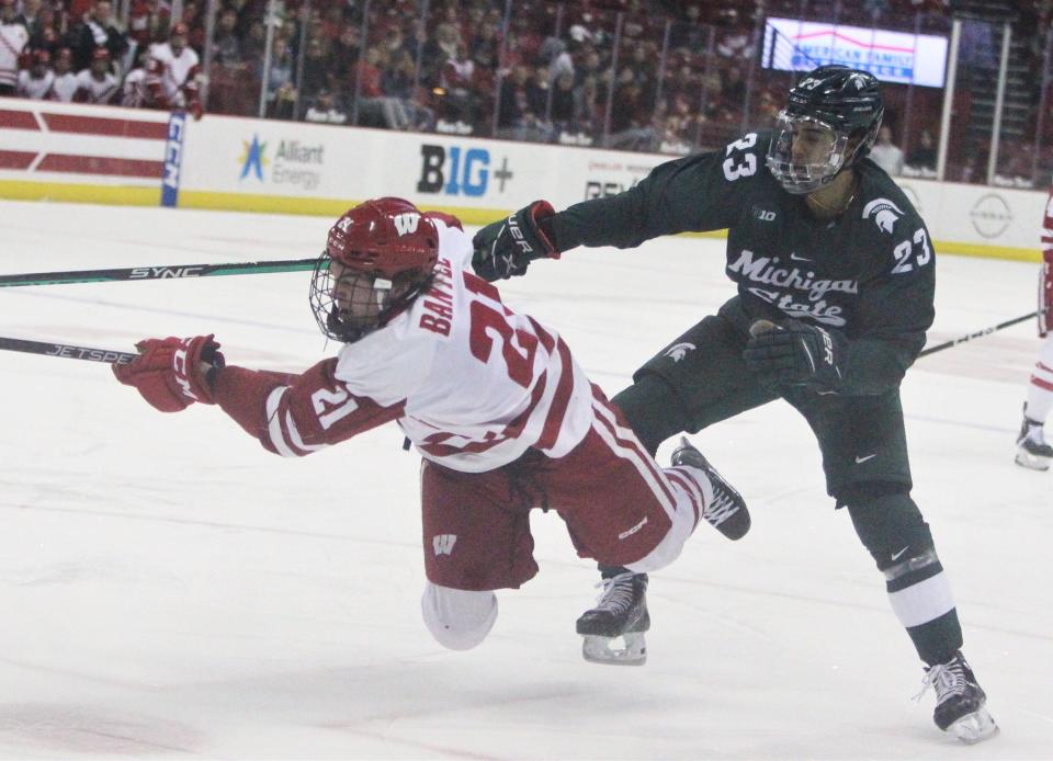 Wisconsin's Carson Bantle (21) falls to the ice after getting tangled up with Michigan State's Jagger Joshua during the first period of the teams' men's hockey game at the Kohl Center in Madison, Wis. on Friday Feb. 17, 2023.