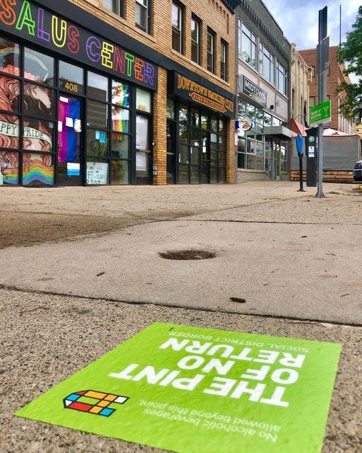 Bright colored signs show the boundaries for the downtown Lansing social district, made permanent earlier this year. Patrons at participating establishments can take adult beverages outside to enjoy in outdoor common areas or events.