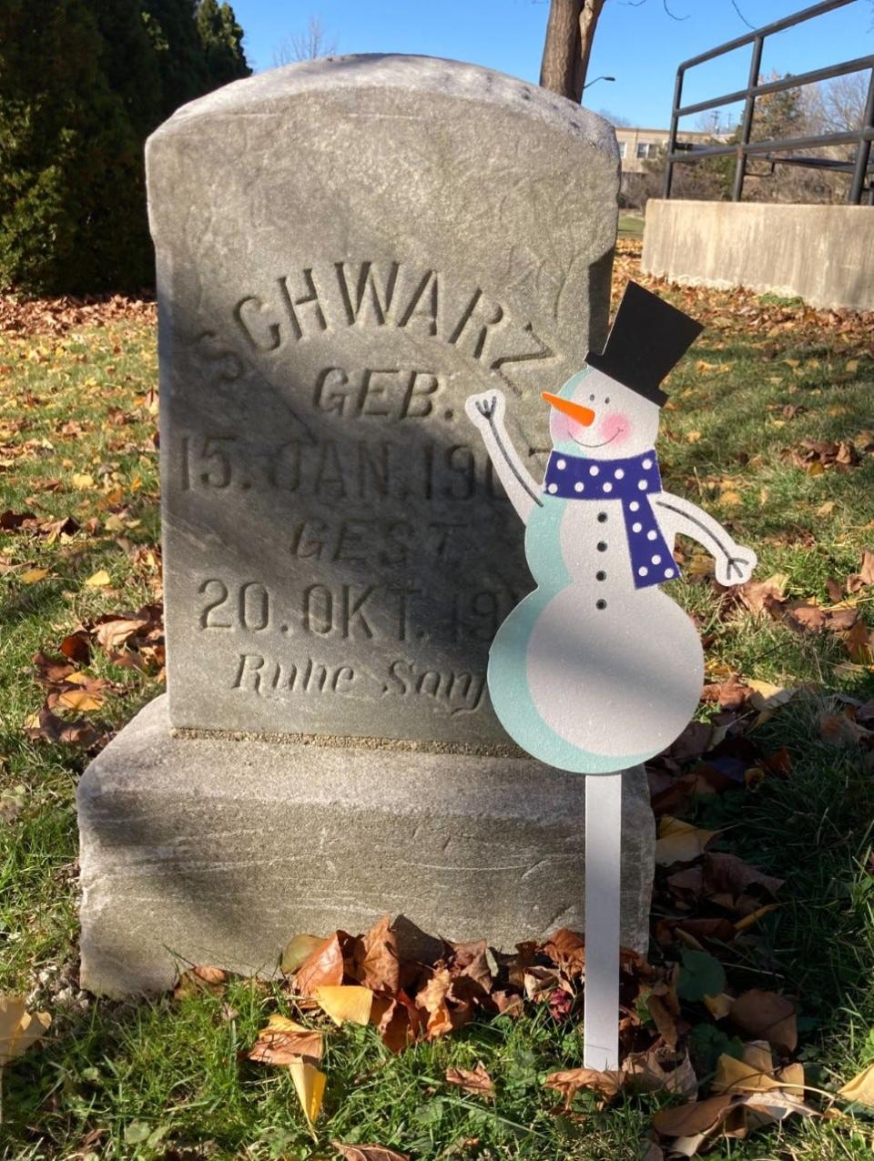 A snowman placed near a gravestone at Honey Creek Cemetery in West Allis is one of many holiday decorations that residents have added to markers at the historic cemetery.