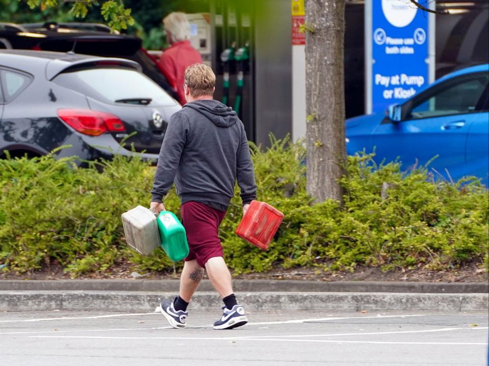 A man carrying multiple fuel containers at a Tesco petrol station in Bracknell, Berkshire (PA)