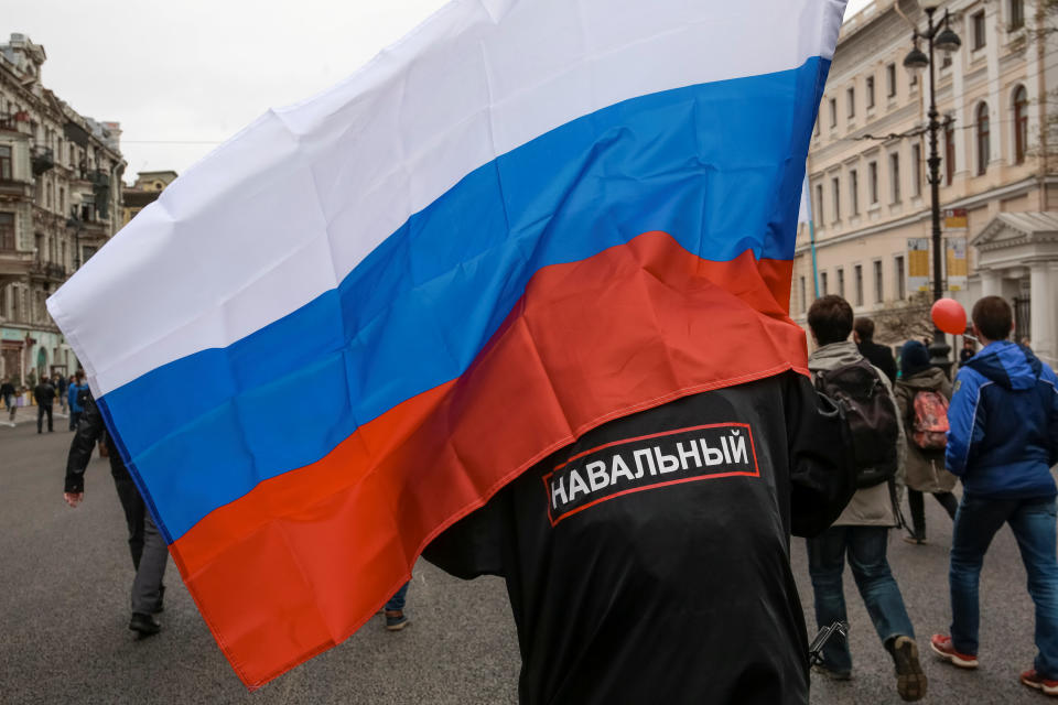 A supporter of Russian opposition leader Alexei Navalny carries a national flag as he attends a protest rally ahead of President Vladimir Putin's inauguration ceremony, in St. Petersburg, Russia May 5, 2018. The writing on his back reads in Russian "Navalny". REUTERS/Anton Vaganov