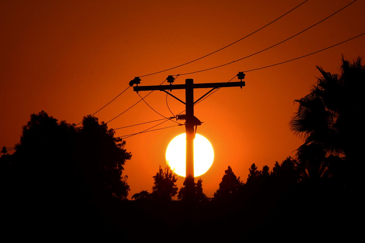 The sun sets behind power lines in Los Angeles