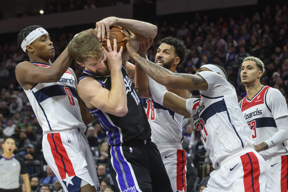 Washington Wizards guard Bilal Coulibaly, left, forward Anthony Gill and center Daniel Gafford battle for a rebound with Sacramento Kings forward Domantas Sabonis during the second half of an NBA basketball game in Sacramento, Calif., Monday, Dec. 18, 2023. The Kings won 143-131. (AP Photo/Randall Benton)