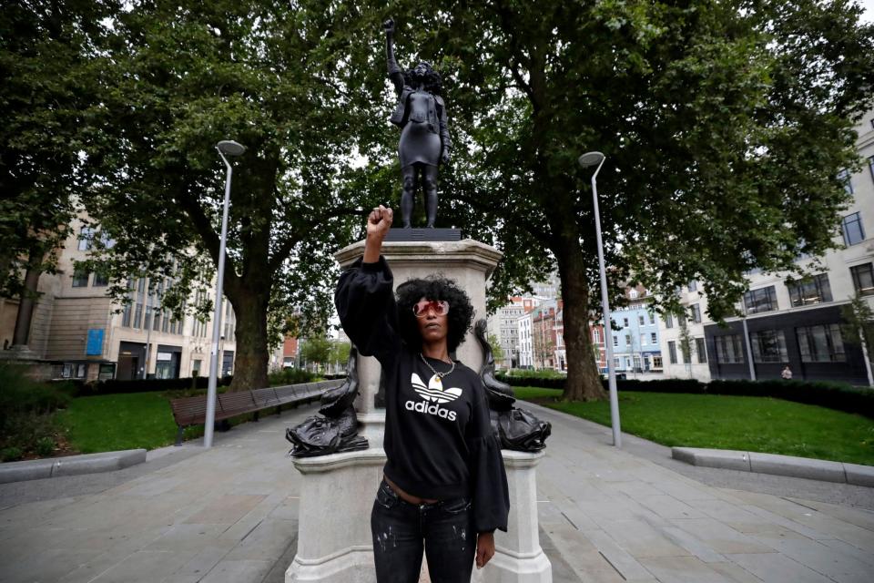 Jen Reid stands in front of the new statue portraying her (AP)