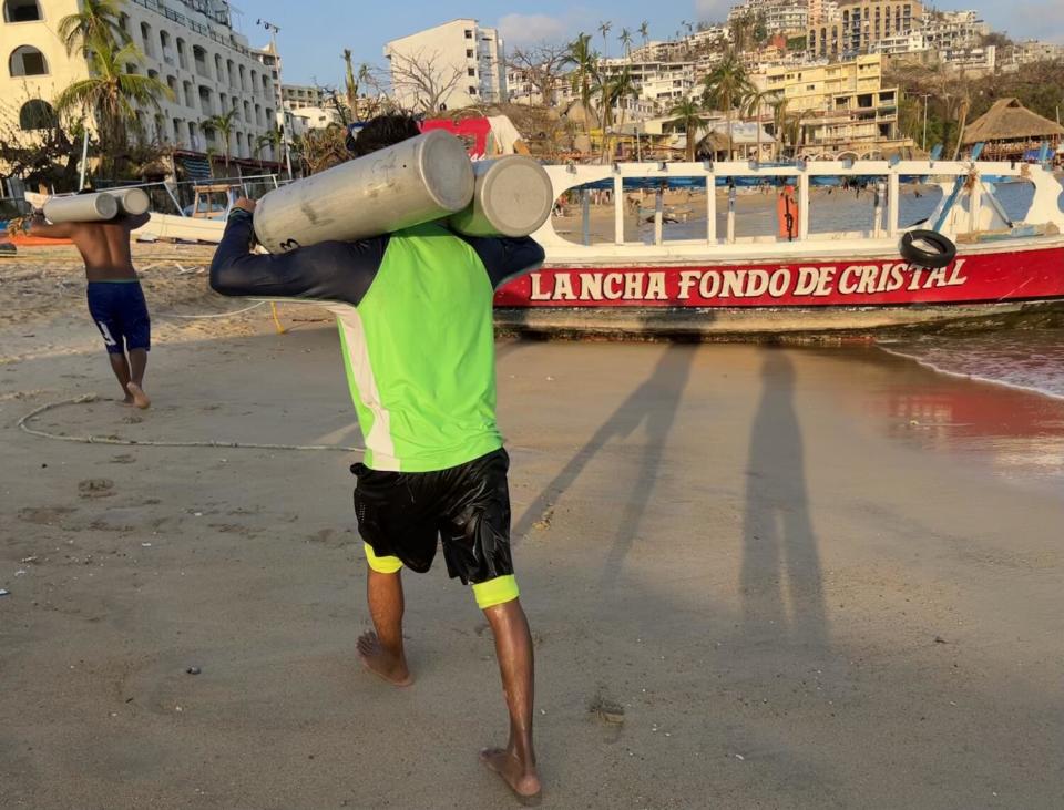 Divers walk on the beach with oxygen tanks.