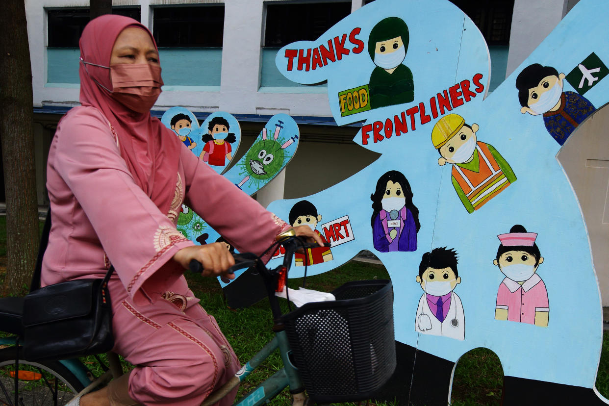 A woman wearing protective mask cycles past an art installation paying homage to the frontliners amid the COVID-19 pandemic on November 14, 2021 in Singapore.  (Photo by Suhaimi Abdullah/NurPhoto via Getty Images)