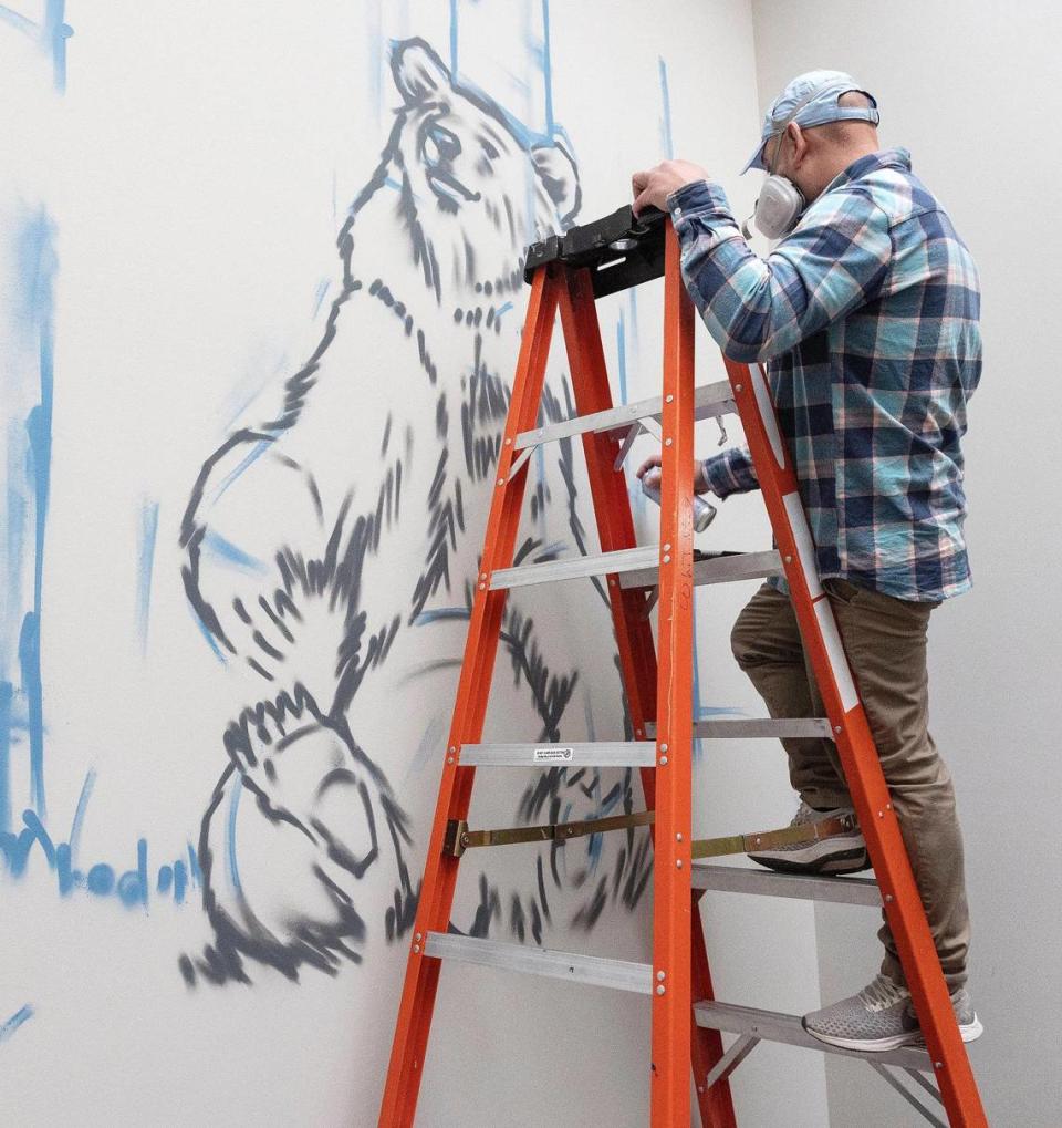 Gaytan paints at Whitney Elementary. He uses a combination of spray paint and brushes for his murals.