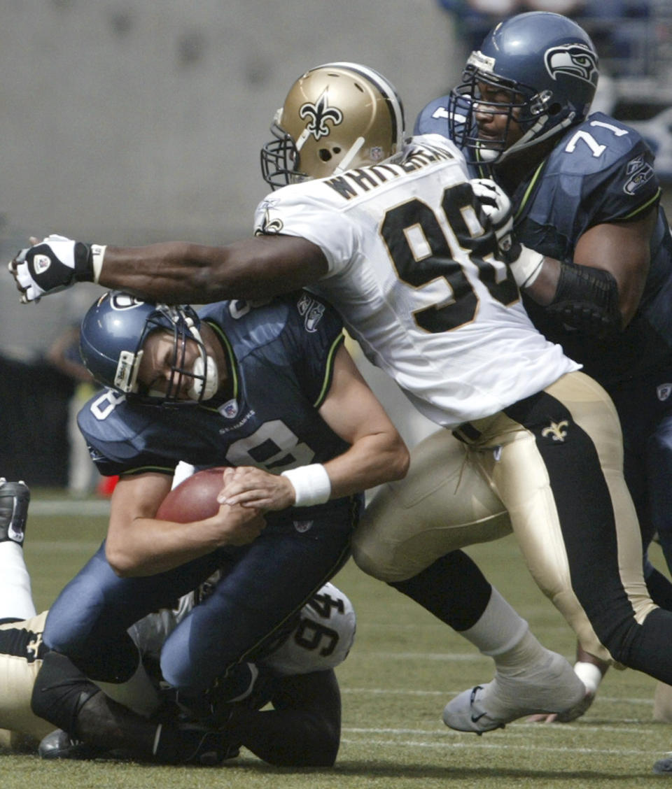 FILE - In this Sept. 7, 2003, file photo, Seattle Seahawks quarterback Matt Hasselbeck is sacked by New Orleans Saints defenders Charles Grant (94) and Willie Whitehead (98) during an NFL football game in Seattle. Whitehead is among four former players who have filed the latest lawsuit claiming the NFL didn't properly protect its players from concussions, citing the bounties paid to New Orleans Saints players for hard hits as just the most recent evidence of the league's violent culture. Ex-players Myron Guyton, Lomas Brown, Jessie Small and Whitehead do not claim in their lawsuit to be victims of Williams' bounty system but cite it as the latest example of a culture that has left former players with debilitating conditions. (AP Photo/Jim Bryant, File)
