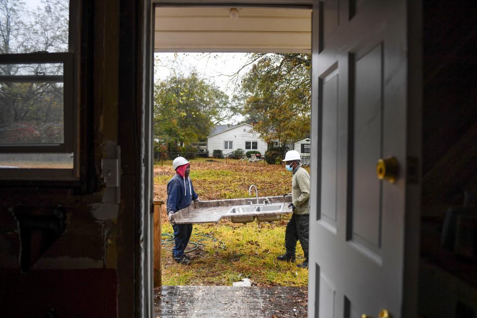 Mike Gambrell, 59, left, and Easu Aiken, 61, carry a countertop and sink from a house to be reused on Tuesday, Nov. 21, 2023. Soteria at Work, a work program through Soteria Community Development Corporation, will reuse wood and other pieces of the house that would otherwise be demolished and put into a landfill.