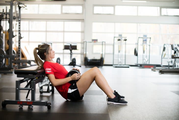 Athlete sits on gym floor for hip thrust exercise