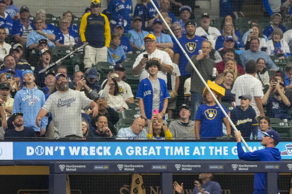 Someone on the Toronto Blue Jays bench tries to get Vladimir Guerrero Jr.'s bat down from a net during the sixth inning of a baseball game against the Milwaukee Brewers Monday, June 10, 2024, in Milwaukee. (AP Photo/Morry Gash)