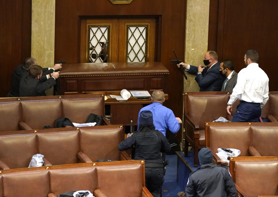 U.S. Capitol police officers point their guns at a door that was vandalized in the House Chamber during a joint session of Congress. (Drew Angerer/Getty Images)