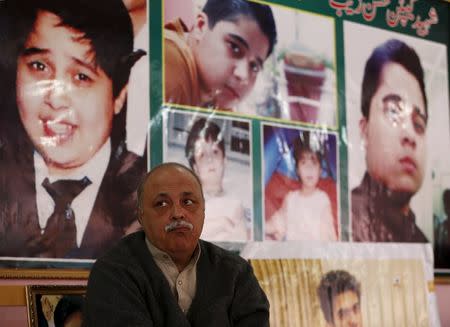 Dr. Farooq Shah, father of Mobin Shah, sits beneath pictures of Hassan Zeb in the rooftop shrine for Hassan Zeb in Peshawar, Pakistan December 11, 2015. REUTERS/Caren Firouz