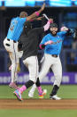 Miami Marlins' Bryan De La Cruz (14) and Edward Cabrera, center, celebrate with Emmanuel Rivera, right, after Rivera hit a single scoring Nick Fortes to beat the Philadelphia Phillies 7-6 in the 10th inning of a baseball game, Sunday, May 12, 2024, in Miami. (AP Photo/Wilfredo Lee)