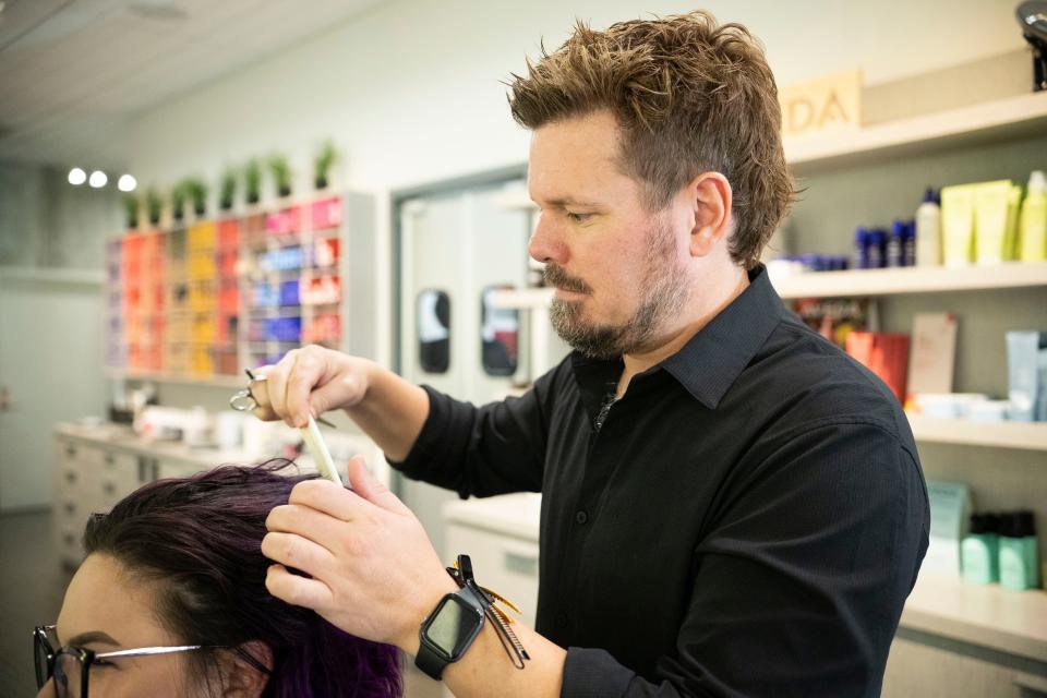 Chris Knudsen, owner of Mane Attraction, is pictured working at his hair salon that he co-owns with his wife.