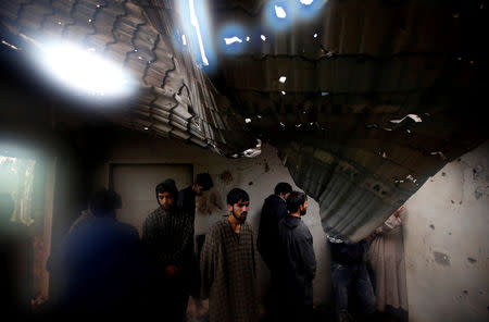 People stand beneath the damaged rooftop of a residential house that was damaged during a gun battle between Zakir Rashid Bhat also known as Zakir Musa, the leader of an al Qaeda affiliated militant group in Kashmir, and Indian security forces on Thursday, in Dadasara village in south Kashmir's Tral May 24, 2019. REUTERS/Danish Ismail TPX IMAGES OF THE DAY