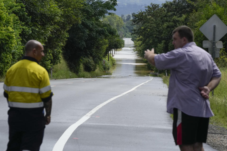 Two men gesture as they look at a flooded road at north Richmond on the outskirts of Sydney, Australia, Thursday, March 3, 2022.Tens of thousands of people had been ordered to evacuate their homes and many more had been told to prepare to flee as parts of Australia's southeast coast are inundated by the worst flooding in decades. (AP Photo/Rick Rycroft)