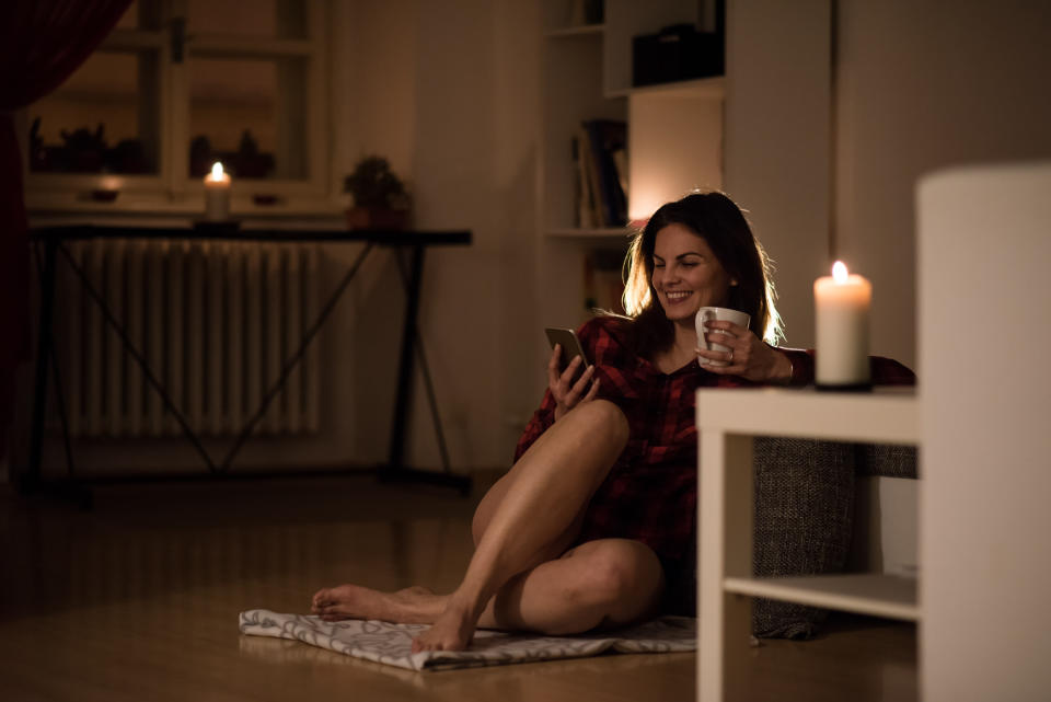 Woman having coffee while using her touchscreen phone