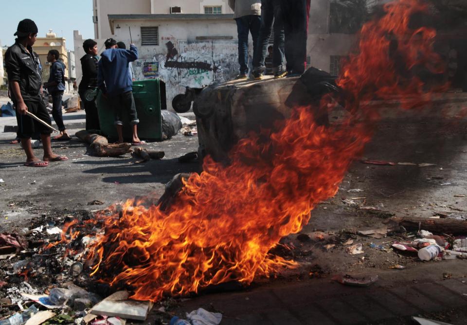 Bahraini anti-government protesters wait for riot police between clashes in the debris-filled main street of Malkiya, Bahrain, Thursday, Feb. 13, 2014. Rubbish and oil smeared on the road are meant to deter police jeeps from entering the village, where shops were shuttered in observance of a general strike called by anti-government groups in the run-up to Friday's third anniversary of the pro-democracy uprising in the Gulf island kingdom. (AP Photo/Hasan Jamali)