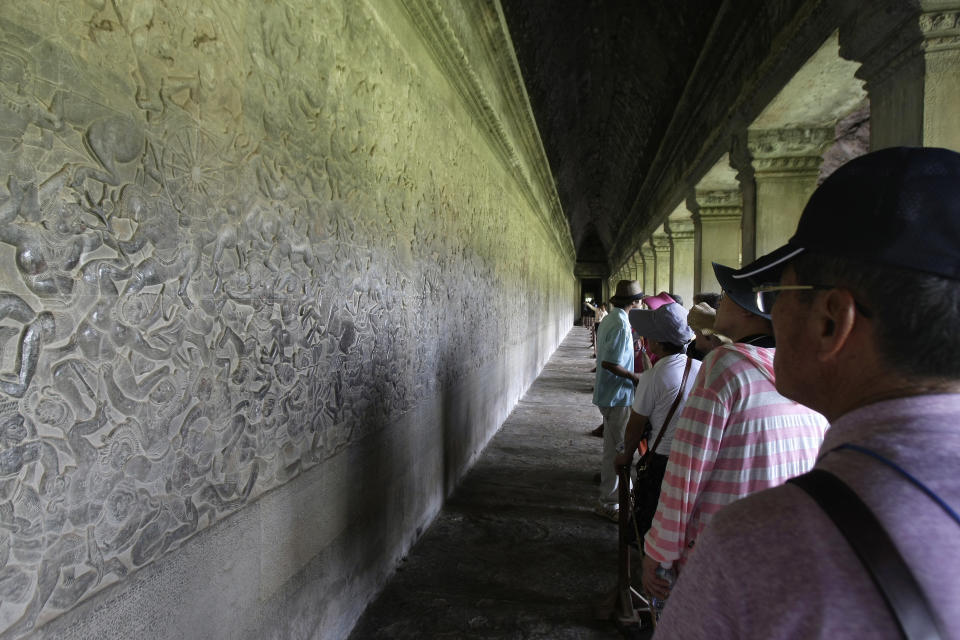FILE - In this July 19, 2012 photo, tourists tour the Angkor Wat temple complex in Siem Reap, some 230 kilometers (143 miles) northwest of Phnom Penh, Cambodia. Cambodia has joined hands with Australia in an effort to use the Internet to help preserve its fabled Angkor Wat temple complex. The Australian Embassy announced Thursday, July 4, 2013, that a recently-opened website, angkorsunsets.com, will allow tourists to generate recommendations for where in the 160-square-mile (400-square-kilometer) complex one can watch spectacular sunsets. (AP Photo/Heng Sinith, File)