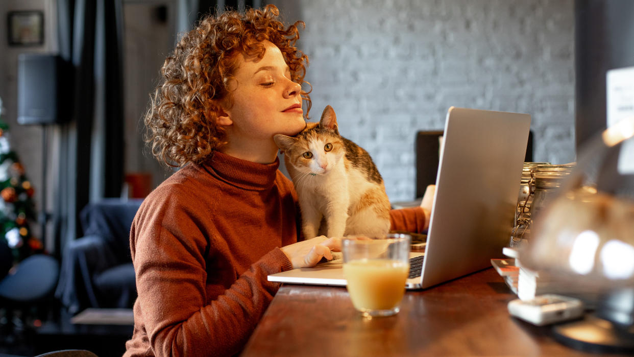 Young woman with cat using laptop.