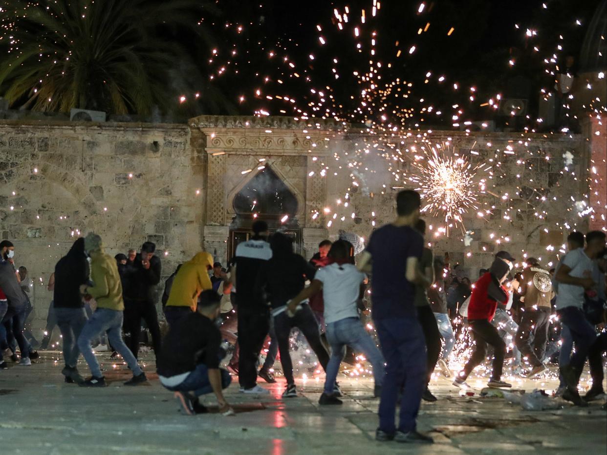 Palestinians react as Israeli police fire stun grenades during clashes at the compound that houses Al-Aqsa Mosque (REUTERS)